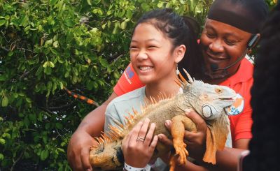 Girl smiling, holding a big iguana